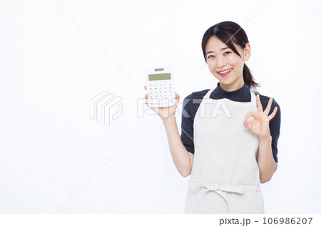 白い背景の前で電卓を持ちOKサインをしている30代の主婦 白い背景の前で電卓を持ちOKサインをしている30代の主婦 106986207