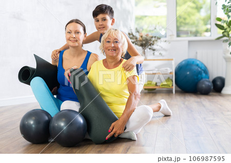 Three people of different ages engaged in yoga sitting on the floor in training room Three people of different ages engaged in yoga sitting on the floor in training room 106987595