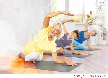 Family three generations do half lotus position Sidhasana with body tilt Family three generations do half lotus position Sidhasana with body tilt 106987793