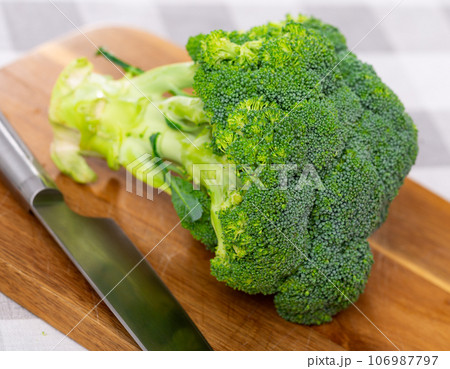Green raw broccoli head lying on wooden cutting board 106987797