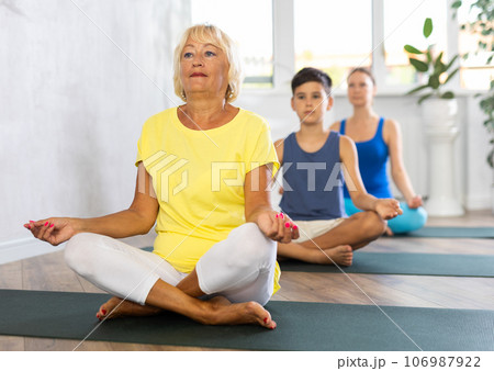 Group of people generation on mats doing yoga exercise lord of fishes pose. 106987922
