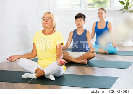 Family three generations do half lotus position Sidhasana with hands clasped in mudra of knowledge 106988001