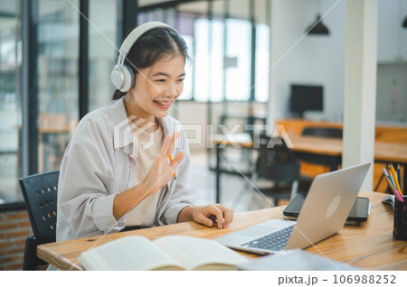 Teenage Asian students  wearing a headphone are communicating through video conferencing for online learning. In a video conference call via apps. 106988252