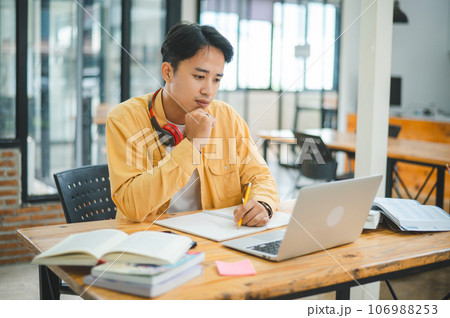 Young Asian college student working and learning on laptop In the cafe. Searching for knowledge online. 106988253