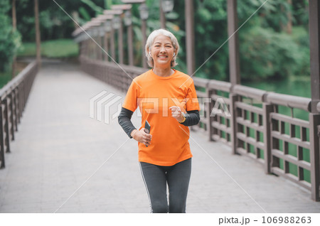 white-haired elderly person exercising in the park early in the morning. 106988263