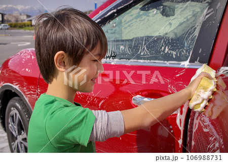 a young boy washing a red car a young boy washing a red car 106988731