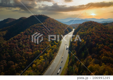 View from above of I-40 freeway in North Carolina heading to Asheville through Appalachian mountains in golden fall season with fast driving trucks and cars. Interstate transportation concept View from above of I-40 freeway in North Carolina heading to Asheville through Appalachian mountains in golden fall season with fast driving trucks and cars. Interstate transportation concept 106991285