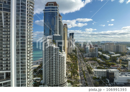 Sunny Isles Beach city with street traffic and luxurious highrise hotels and condos on Atlantic ocean shore. American tourism infrastructure in southern Florida 106991393