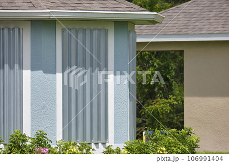 Steel sheets mounted as storm shutters for hurricane protection of house windows. Protective measures before natural disaster in Florida 106991404