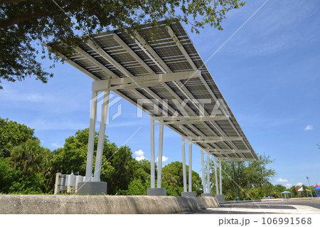 Solar panels installed as shade roof over parking lot for parked electric cars for effective generation of clean electricity. Photovoltaic technology integrated in urban infrastructure 106991568