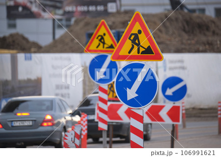 Roadworks warning traffic signs of construction work on city street and slowly moving cars 106991621