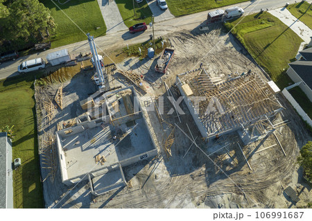 Professional builders and crane truck working on roof construction of unfinished suburban home with wooden frame structure in Florida rural area. Concept of housing development in America Professional builders and crane truck working on roof construction of unfinished suburban home with wooden frame structure in Florida rural area. Concept of housing development in America 106991687