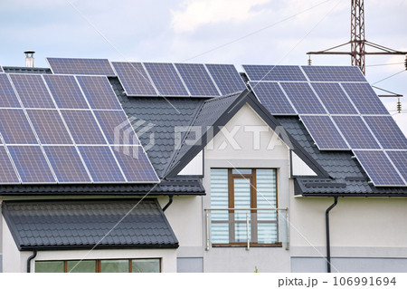 Private home roof covered with solar photovoltaic panels for generating of clean ecological electric energy in suburban rural town area. Concept of autonomous house 106991694