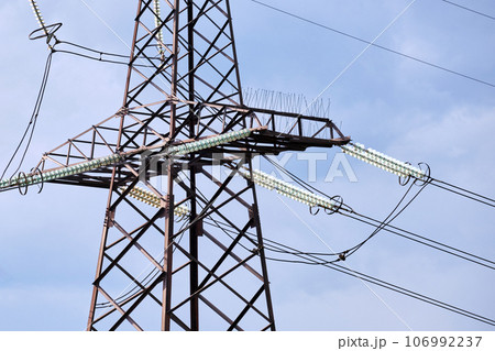 High voltage tower with electric power lines divided by safe guard bushing transfening safely electrical energy through cable wires. Electricity transmission on long distance concept 106992237