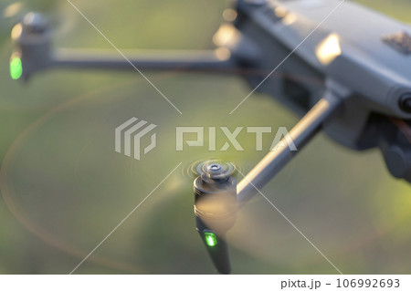 Drone quadcopter with digital camera and fast rotating propellers flying taking video and pictures 106992693