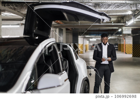 Adult in business suit thumbing through cash in EV parking Adult in business suit thumbing through cash in EV parking 106992698
