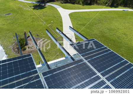 Damaged by hurricane wind photovoltaic solar panels mounted on parking lot canopy roof for producing green ecological electricity. Consequences of natural disaster in Florida, USA 106992801