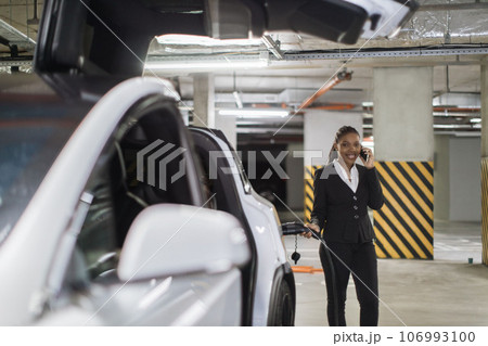 Worker speaking on phone at EV charge point in public garage Worker speaking on phone at EV charge point in public garage 106993100