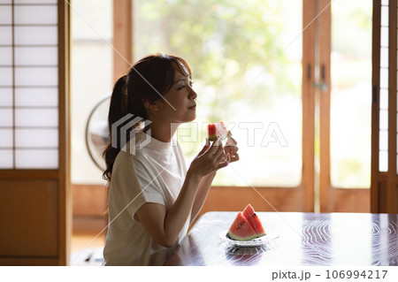 実家でスイカを食べる女性 106994217