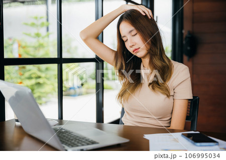 Tired office woman sitting at desk touching massaging stiff neck while holding her head in cafe, Asian business woman suffering from neck ache pain caused by sitting working long time laptop usage 106995034