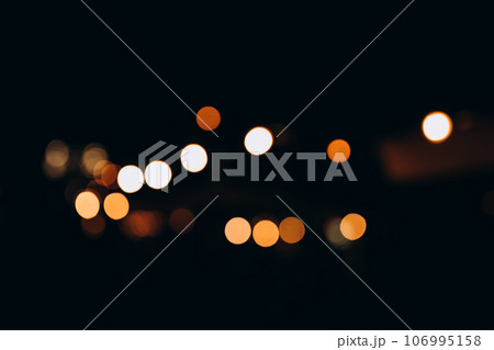 Decorative string lights at night time, Defocused Background, night city life backdrop, party time with Yellow bokeh balls. Warm festive bokeh of string lights over an outdoor bar or patio at twilight 106995158