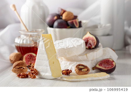 Camembert cheese with figs, walnuts, and honey on a white table. 106995419