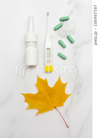 Autumn seasonal cold and illness. Antibiotics, nose spray and thermometer. Marble background. Top view. Flat lay. Care and health and treatment plan. Vertical photography. 106997597