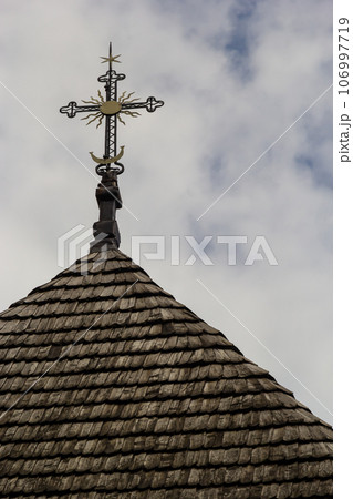 old wooden church against the blue sky in Ukraine, wooden roof with a cross 106997719
