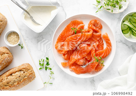 Salted salmon sliced on plate on a white background, top down view Salted salmon sliced on plate on a white background, top down view 106998492