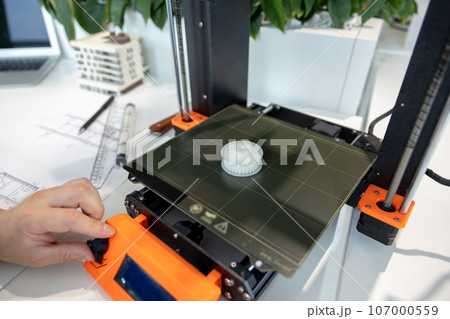 Man checking 3d printer, process of making things on 3d printer in laboratory. 107000559