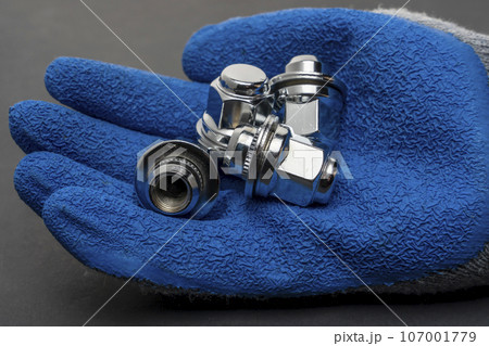 Shiny new wheel nuts in the hand of a car mechanic Shiny new wheel nuts in the hand of a car mechanic 107001779