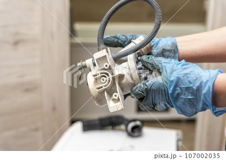 a broken old washing machine water pump in the hands of repairman 107002035