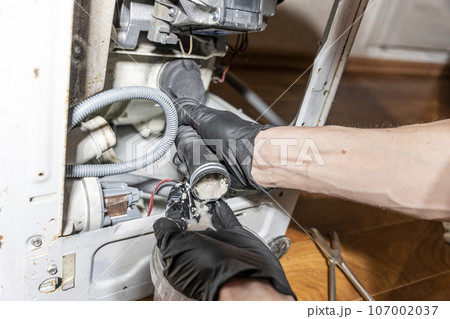 A repairman repairs a used washing machine 107002037