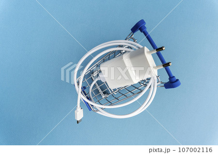A phone charger in a supermarket cart on a blue background 107002116