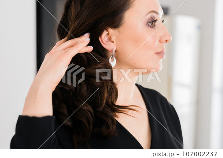 Detail of young woman wearing beautiful luxury earring. Handmade jewellery and accessories Detail of young woman wearing beautiful luxury earring. Handmade jewellery and accessories 107002237