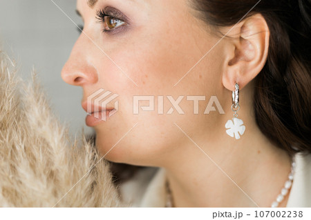 Detail of young woman wearing beautiful luxury earring. Handmade jewellery and accessories Detail of young woman wearing beautiful luxury earring. Handmade jewellery and accessories 107002238