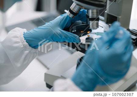 Science and medicine, scientist analyzing and dropping a sample into a glassware, experiments containing chemical liquid in laboratory on glassware, innovative and technology. 107002307