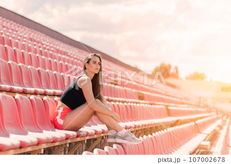 A female coach with dark hair stands on the red running track of the stadium 107002678