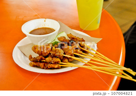 Famous Singaporean Chicken Satay skewers BBQ in a food court hawker center served in white dish 107004821