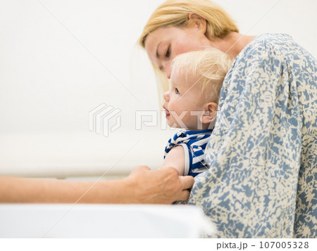 child beeing vaccinated by pediatrician in presence of his mother. Preventive vaccination against Diphtheria, whooping cough, tetanus, hepatitis, haemophilus influenzae, pneumococcus, poliomyelitis. 107005328