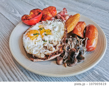 English Big Breakfast with sunny fried eggs, sausage, bacon, tomatos, hash brown, mushroom English Big Breakfast with sunny fried eggs, sausage, bacon, tomatos, hash brown, mushroom 107005619