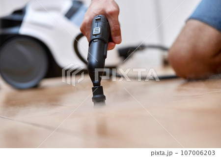 male hand with professional cleaning steam generator cleaning tiled floor 107006203