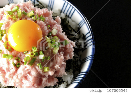 刻み海苔と卵黄とネギトロの丼ぶりを黒背景で俯瞰撮影 107006545