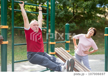 Elderly man and a woman do exercises on sports bars 107006697