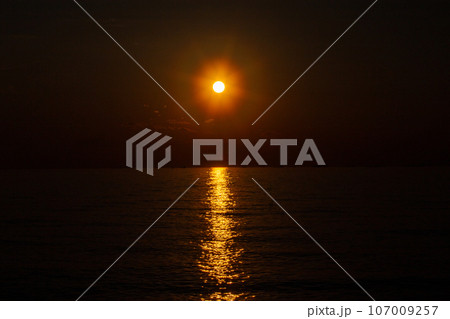 真っ赤に輝く太陽と海に反射する夕陽の光の道 真っ赤に輝く太陽と海に反射する夕陽の光の道 107009257