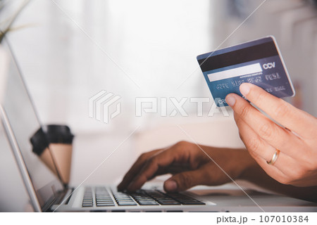 Online shopping. Woman hands holding credit card and using laptop with product purchase at home, female register via credit cards on computer to make electronic payment security online Online shopping. Woman hands holding credit card and using laptop with product purchase at home, female register via credit cards on computer to make electronic payment security online 107010384