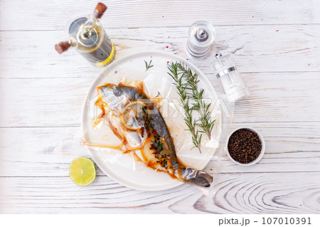 Raw fish dorado with spices and herbs ingredients on white background Raw fish dorado with spices and herbs ingredients on white background 107010391