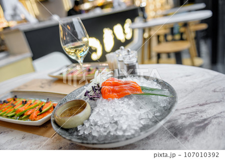 Salmon sashimi plate with sauce and ice on a marble table Salmon sashimi plate with sauce and ice on a marble table 107010392