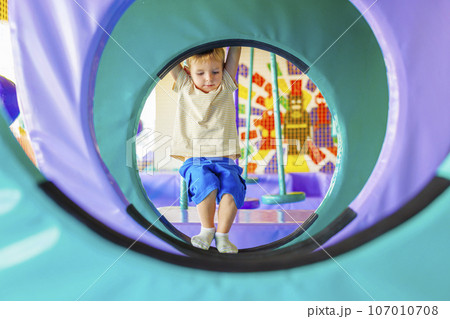 Cute little boy crawling and playing on colorful playground at amusement park Cute little boy crawling and playing on colorful playground at amusement park 107010708