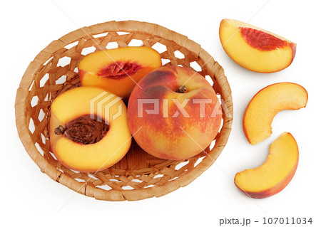 Ripe peach fruit with half in a wicker basket isolated on white background with full depth of field. Top view. Flat lay Ripe peach fruit with half in a wicker basket isolated on white background with full depth of field. Top view. Flat lay 107011034